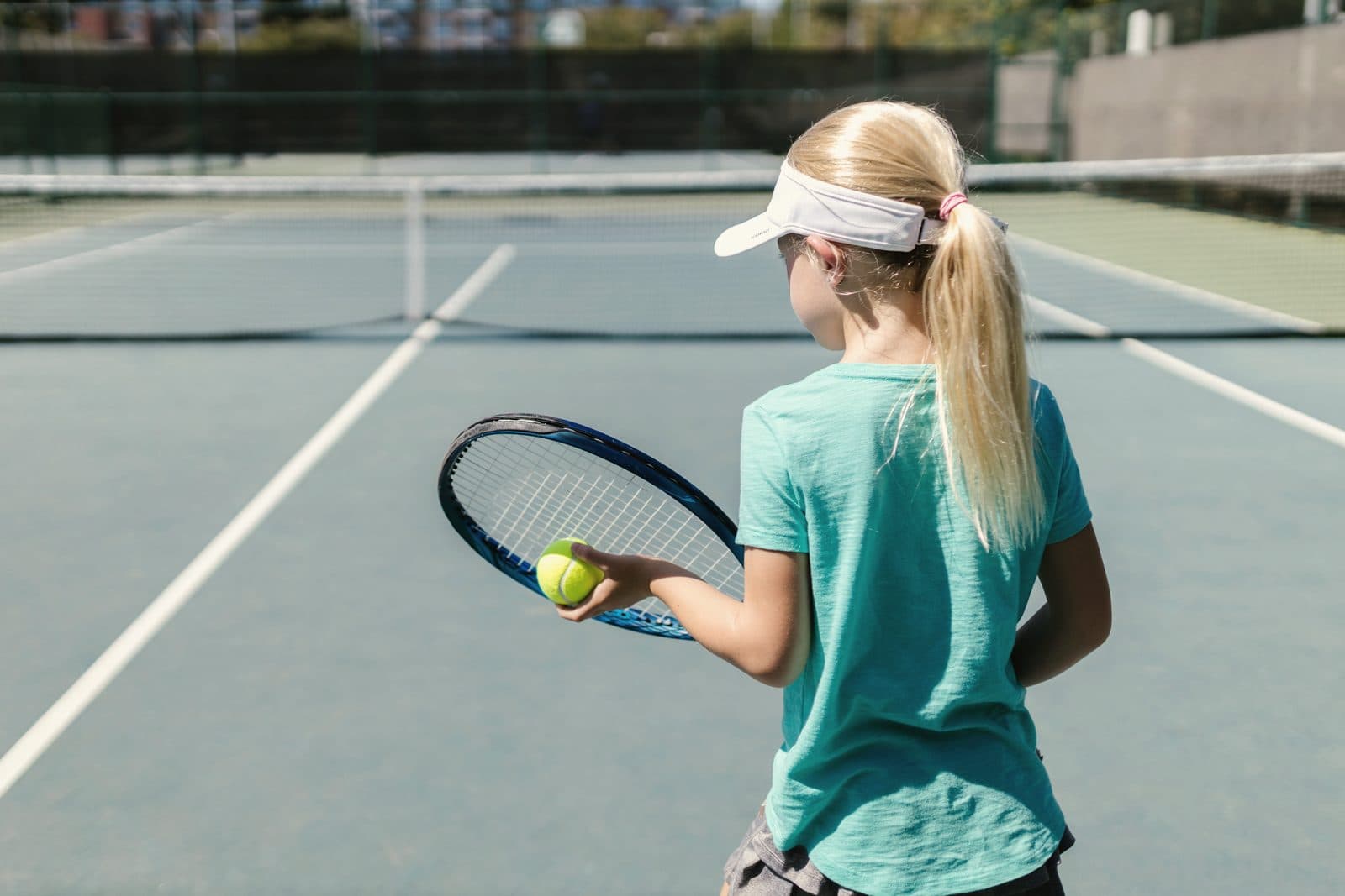 Tenis kortunda servis atmaya hazırlanan genç sporcu
